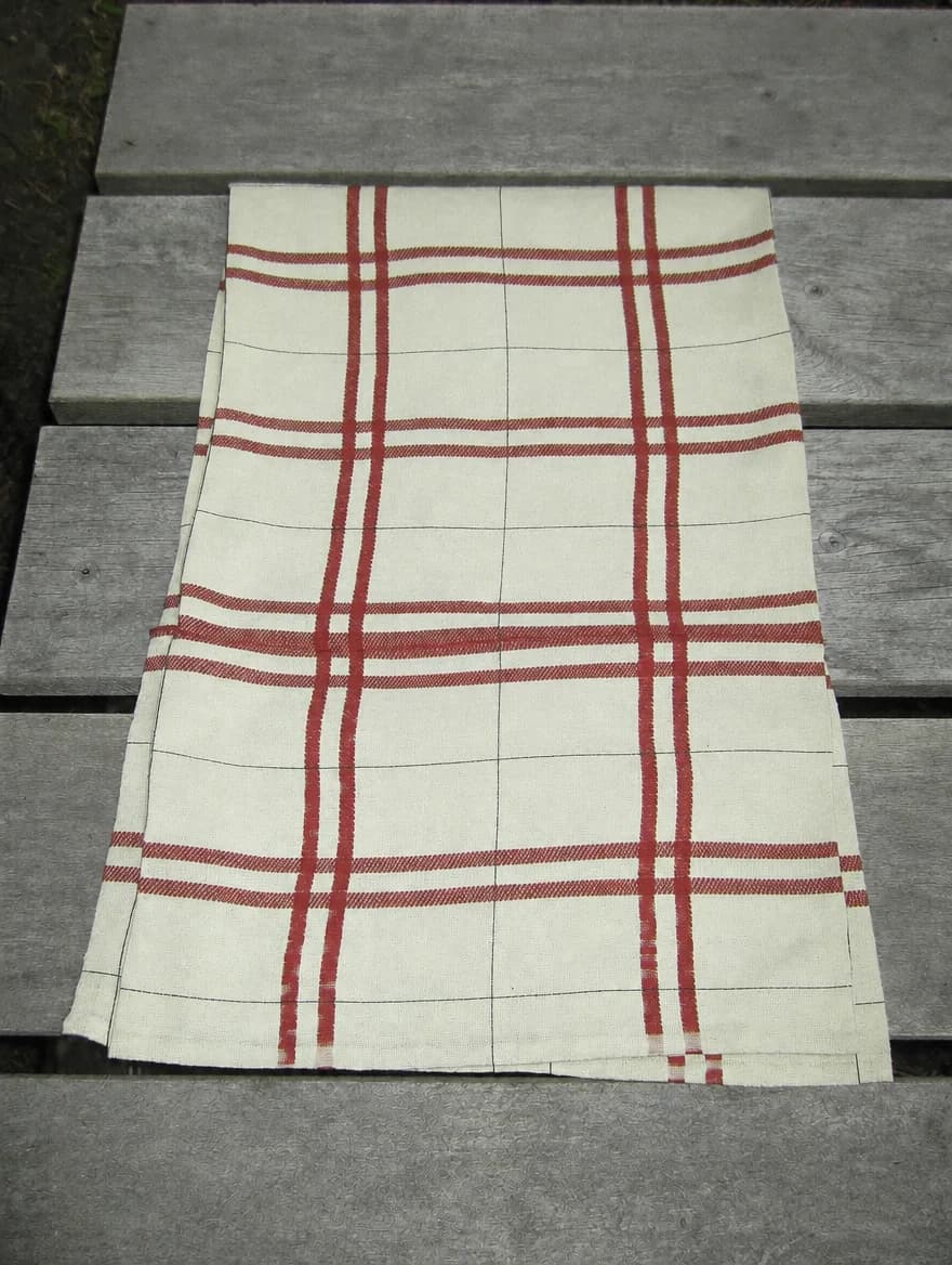 Windowpane Check Towel in Rust / Cream, folded on a wooden garden bench