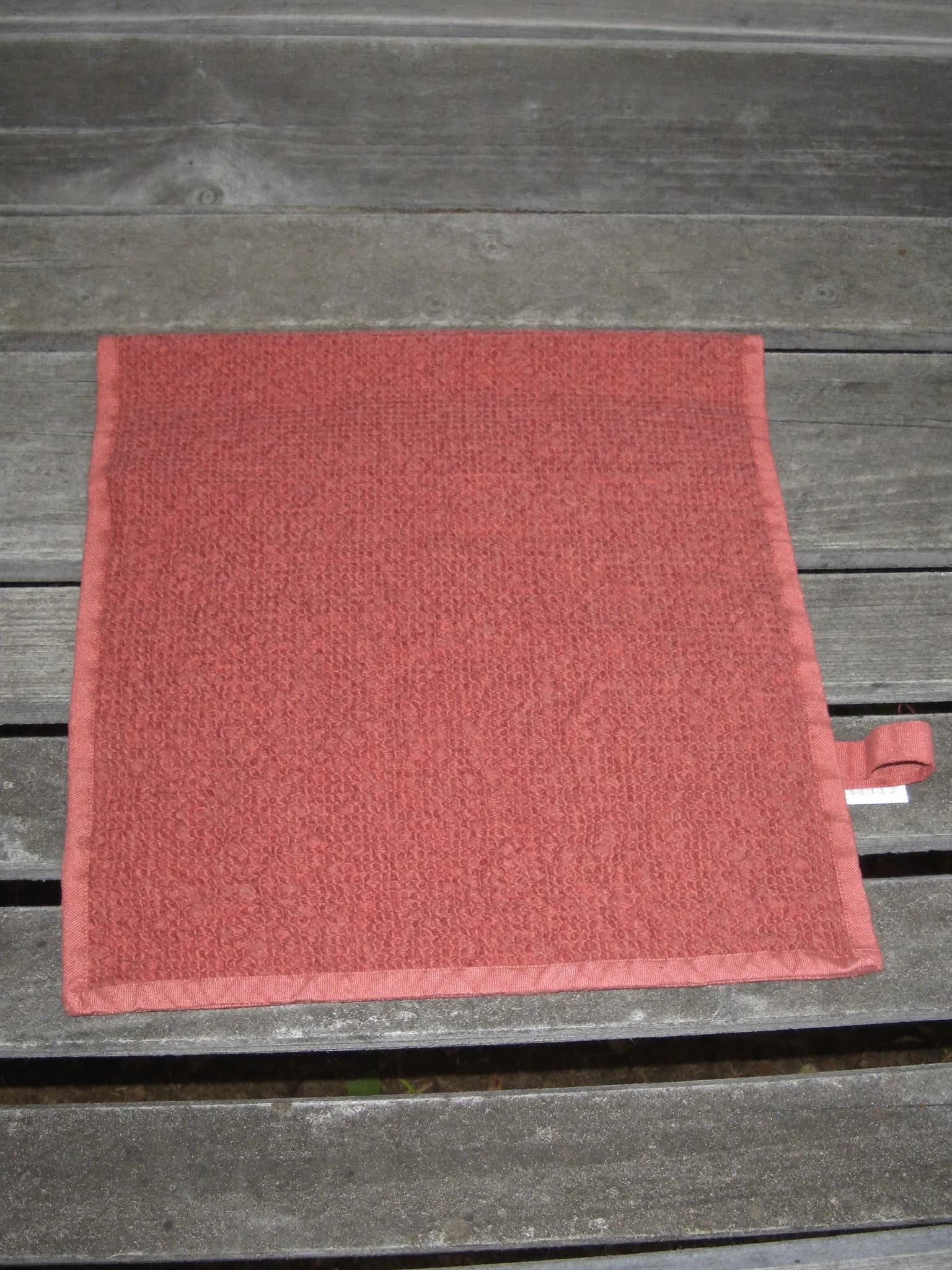 Waffle Towel in Clay, folded on a wooden garden bench